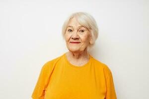 Portrait of an old friendly woman in a yellow t-shirt posing cropped view photo