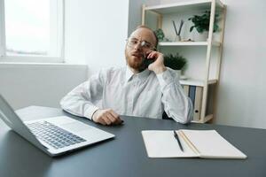A man in a wheelchair a businessman with tattoos in the office works, talking on the phone screaming and angry, integration into society, the concept of working a person with disabilities photo
