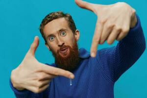 Portrait of a man in a sweater smile and happiness, hand signs and symbols, on a blue background. Lifestyle positive, copy place. photo