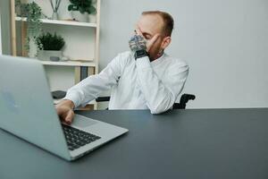 A man wheelchair, a businessman in an office at a laptop, fatigue and emotional burnout at the end of the working day, the concept of working a person with disabilities, freedom from social frameworks photo