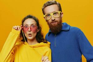 Man and woman couple smiling cheerfully and crooked with glasses, on yellow background, symbols signs and hand gestures, family shoot, newlyweds. photo