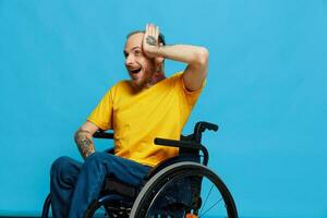un hombre en un silla de ruedas sorprendido y abierto boca en un camiseta con tatuajes en su brazos se sienta en un azul estudio fondo, un lleno vida, un real persona foto