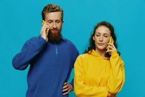 Woman and man cheerful couple with phones in their hands crooked smile cheerful, on blue background. The concept of real family relationships, talking on the phone, work online. photo