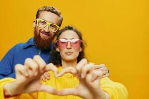 hombre y mujer Pareja sonriente alegremente y torcido con anteojos, en amarillo fondo, símbolos señales y mano gestos, familia disparar, recién casados. foto