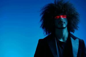 Fashion portrait of a man with curly hair on a blue background with a red stripe of light, multicolored light, trendy, modern concept. photo