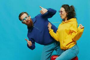 Woman and man smile sitting on suitcase with red suitcase smile, on blue background, packing for trip, family vacation trip. photo