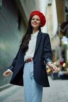 Fashion woman smile with teeth portrait walking tourist in stylish clothes in jacket with red lips walking down narrow city street flying hair, travel, cinematic color, retro vintage style. photo