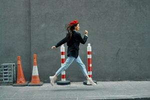 Fashion woman running down the street in front of the city tourist in stylish clothes with red lips and red beret, travel, cinematic color, retro vintage style. photo