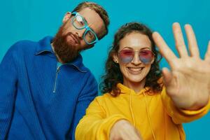 A woman and a man fun couple cranking and showing signs with their hands smiling cheerfully, on a blue background, The concept of a real relationship in a family. photo