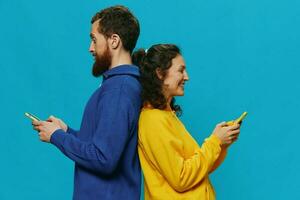 Woman and man cheerful couple with phones in their hands crooked smile cheerful, on blue background. The concept of real family relationships, talking on the phone, work online. photo