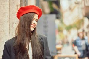 mujer sonrisa Moda modelo camina en el calle en el ciudad centrar entre el multitud en un chaqueta y rojo boina y vaqueros, cinematográfico francés Moda estilo ropa, viaje a Estanbul primavera foto