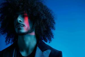 Fashion portrait of a man with curly hair on a blue background, multinational, colored light, trendy, modern concept. photo