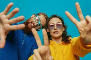 A woman and a man fun couple cranking and showing signs with their hands smiling cheerfully, on a blue background, The concept of a real relationship in a family. photo