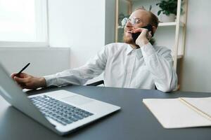 A man in a wheelchair businessman with tattoos in the office works, talking on the phone and smiling, integration into society, the concept of working a person with disabilities photo