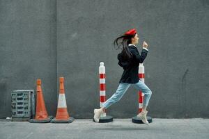 Fashion woman running down the street in front of the city tourist in stylish clothes with red lips and red beret, travel, cinematic color, retro vintage style, late to work. photo