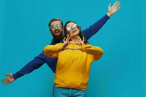 un mujer y un hombre divertido Pareja arrancando y demostración señales con su manos sonriente alegremente, en un azul fondo, el concepto de un real relación en un familia. foto