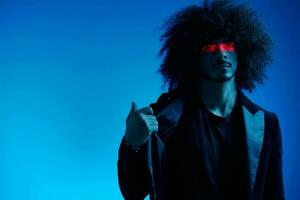 Fashion portrait of a man with curly hair on a blue background with a red stripe of light, multicolored light, trendy, modern concept. photo