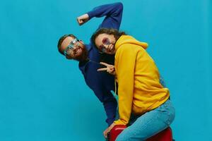 Woman and man smile sitting on suitcase with red suitcase smile, on blue background, packing for trip, family vacation trip. photo