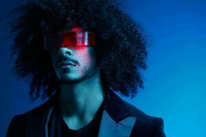 Fashion portrait of a man with curly hair on a blue background wearing red sunglasses, multinational, colored light, trendy, modern concept. photo