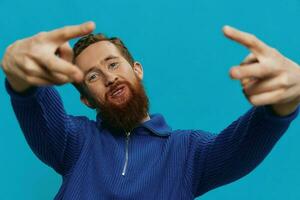 Portrait of a man in a sweater smile and happiness, hand signs and symbols, on a blue background. Lifestyle positive, copy place. photo