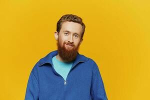 Portrait of a man smiling in a blue sweater on a yellow background copy space, space for text photo