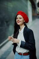 Fashion woman smile with teeth portrait walking tourist in stylish clothes in jacket with red lips walking down narrow city street flying hair, travel, cinematic color, retro vintage style. photo