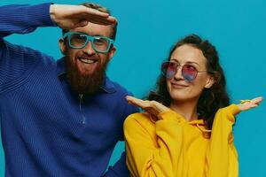 un mujer y un hombre divertido Pareja arrancando y demostración señales con su manos sonriente alegremente, en un azul fondo, el concepto de un real relación en un familia. foto