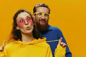 hombre y mujer Pareja sonriente alegremente y torcido con anteojos, en amarillo fondo, símbolos señales y mano gestos, familia disparar, recién casados. foto