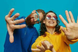 un mujer y un hombre divertido Pareja arrancando y demostración señales con su manos sonriente alegremente, en un azul fondo, el concepto de un real relación en un familia. foto