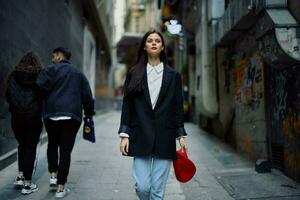 Fashion woman tourist in stylish clothes in a jacket and red beret walking down a narrow city street flying hair and happy travel, French style, cinematic color, retro style. photo