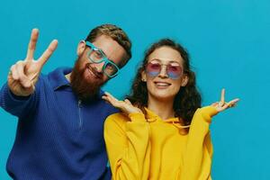 un mujer y un hombre divertido Pareja arrancando y demostración señales con su manos sonriente alegremente, en un azul fondo, el concepto de un real relación en un familia. foto