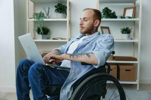 Man wheelchair freelancer working at laptop at home smile, working online, social networks and startup, copy space, integration into society, health concept man with disabilities, real person close-up photo