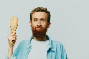 retrato de un hombre con un masaje peine en su manos, peinada su pelo y barba, pelo pérdida problema foto