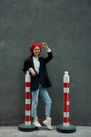 Fashion woman standing on the street in front of the city and road works tourist in stylish clothes with red lips and red beret, travel, cinematic color, retro vintage style. photo