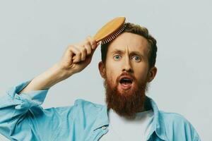 Portrait of a man with a massage comb in his hands, combing his hair and beard, hair loss problem photo