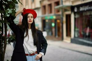 mujer modelo soportes en el calle en el ciudad en un chaqueta y rojo boina, cinematográfico francés Moda estilo ropa, viaje a Estanbul foto