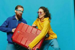 mujer y hombre sonrisa maletas en mano con amarillo y rojo maleta sonrisa divertido, en azul fondo, embalaje para un viaje, familia vacaciones viaje. foto