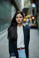 Fashion woman smile with teeth portrait looking at camera tourist in stylish clothes in jacket with red lips walking down narrow city street flying hair, travel, cinematic color, retro vintage style. photo