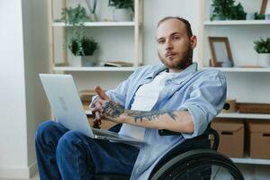 Man in wheelchair freelancer working at laptop at home smile, working online, social networks and startup, copy space, social integration, health concept man with disabilities, real person photo