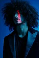 Fashion portrait of a man with curly hair on a blue background, multinational, colored light, trendy, modern concept. photo