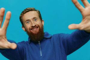 Portrait of a man in a sweater smile and happiness, hand signs and symbols, on a blue background. Lifestyle positive, copy place. photo