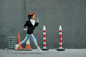 Fashion woman running down the street in front of the city tourist in stylish clothes with red lips and red beret, travel, cinematic color, retro vintage style, late to work. photo