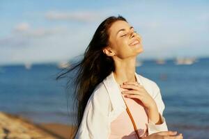 A woman with her eyes closed in the sun on a horse on the ocean smile, flying hair, tanned skin, rest, the concept of skin care in summer and spring. photo