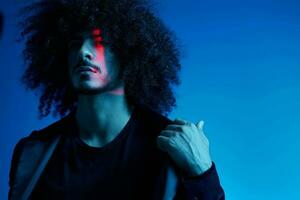 Fashion portrait of a man with curly hair on a blue background, multinational, colored light, trendy, modern concept. photo