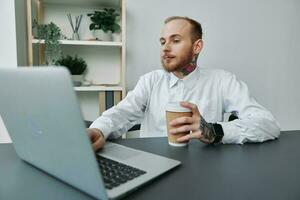 A man in a wheelchair, a businessman with tattoos in the office at a laptop, a coffee break, annoyance, the concept of working a person with disabilities, freedom from social frames photo