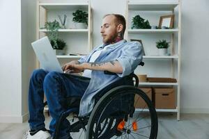 A man in a wheelchair freelancer works at a laptop at home, work online, social networks and startup, copy space, integration into society, concept of health disabled person, real person close-up photo
