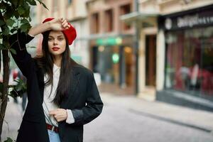 mujer modelo soportes en el calle en el ciudad en un chaqueta y rojo boina, cinematográfico francés Moda estilo ropa, viaje a Estanbul foto