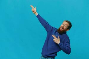 retrato de un hombre en un suéter sonrisa y felicidad, mano señales y símbolos, en un azul antecedentes. estilo de vida positivo, Copiar lugar. foto