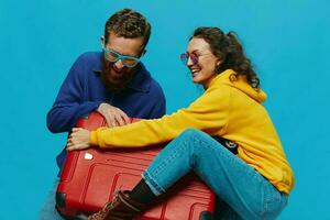 mujer y hombre sonrisa maletas en mano con amarillo y rojo maleta sonrisa divertido, en azul fondo, embalaje para un viaje, familia vacaciones viaje. foto