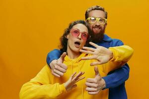 hombre y mujer Pareja sonriente alegremente y torcido con anteojos, en amarillo fondo, símbolos señales y mano gestos, familia disparar, recién casados. foto